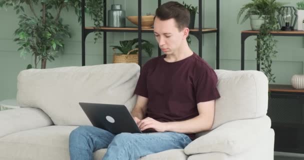 Poważny Mężczyzna Siedzi Kanapie Skupiony Pracy Pisząc Laptopie Jego Uważny — Wideo stockowe