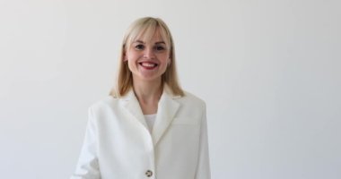 Beyaz arka planda çekici bir kadın görülüyor, baş parmağı ve işaret parmağıyla bir çember oluşturarak iyi bir hareket sergiliyor. Gülüşü ve kendine güveni pozitifliğini ve onayını gösteriyor..