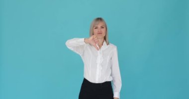 Mutsuz kadın memnuniyetsizliğini dile getirirken sakin mavi bir arka plana başparmak işareti yapıyor. Hoşnutsuzluğu, yüz ifadesinden ve olumsuz el hareketinden anlaşılıyor..