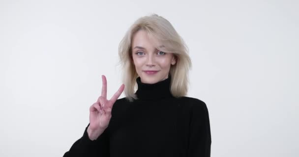 Usmívající Běloška Stojí Bílém Pozadí Usmívá Zvedá Dva Prsty Gestu — Stock video