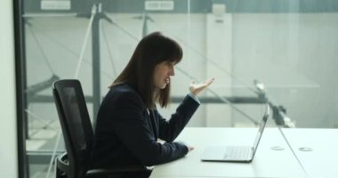 Önemli bir video görüşmesi yapan profesyonel bir kadının ofisi. Odaklanmış bir ifadeyle ve kararlı bir tavırla sohbete dalıp, iş meselelerini verimli bir şekilde tartışır..