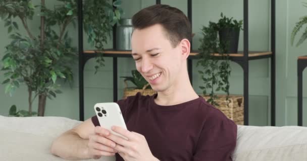 Pohovce Obývacím Pokoji Sedí Usměvavý Muž Drží Telefon Jeho Tvář — Stock video