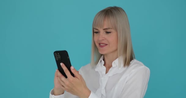 Zakenvrouw Veegt Met Haar Telefoon Tegen Een Serene Blauwe Achtergrond — Stockvideo