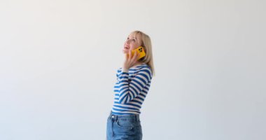 Kadın, temiz beyaz bir arka planda bir telefon konuşmasında görülüyor. Odaklanmış ifadesi ve hareketleri çağrıya aktif olarak katıldığını gösteriyor..