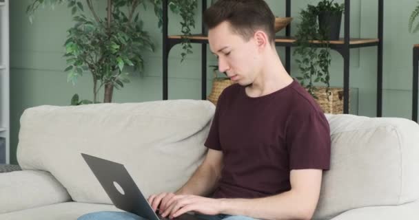 Затишній Обстановці Кавказький Чоловік Сидить Дивані Старанно Працюючи Своїм Ноутбуком — стокове відео