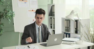 Genç bir ofis çalışanı profesyonel ofis ortamındaki işleri özenle yönetiyor. Masasında oturmuş, titizlikle evrak işleriyle uğraşıyor, belgeleri düzenliyor ve dosyaları düzenliyor..