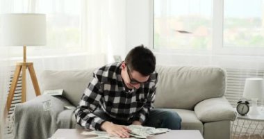 Oturma odasındaki kanepede oturan genç beyaz bir adam neşeyle etrafa para saçıyor. Sahne, onun kaygısız ruhunu ve neşeli bir anı yansıtan tuhaf hareketini yakalıyor..