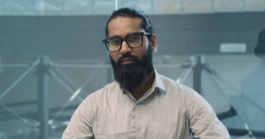 Büyüleyici bir portrede, Hintli bir işadamı kameraya bakarken sıcak bir gülümseme sahneyi alır. Onun dostça ifadesi güven ve yakınlık yayar..