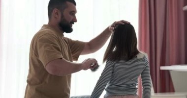 Yürek ısıtan bir sahnede, sevgi dolu bir baba kızının saçlarını nazikçe tarar, aralarındaki bağ açık bir şekilde görülür. Baba dokunuşu ilgi ve şefkat yayar..