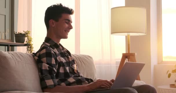 Sofá Sala Estar Homem Caucasiano Alegre Senta Com Seu Laptop — Vídeo de Stock