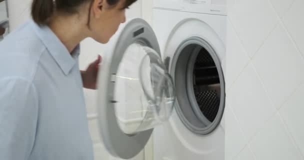 在一种失望的状态中 一个女人对她在洗衣机里洗衣服的结果表示不满 她沮丧的表情反映了她对清洁过程的失望 — 图库视频影像