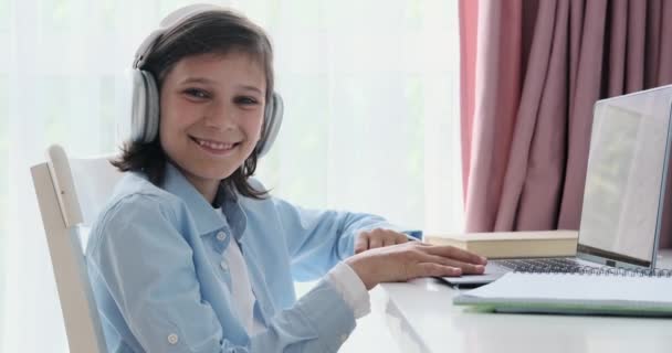 Siedząc Przy Stole Uczeń Nosi Słuchawki Kieruje Ciepły Uśmiech Stronę — Wideo stockowe