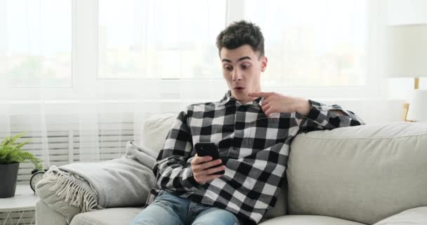 Obývacím Pokoji Překvapený Běloch Rozchechtá Když Používá Telefon Jeho Výraz — Stock video
