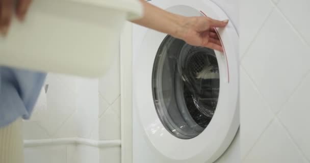 有能な女性は彼女のコアを担当し 洗濯機にグリムの衣服を積み込みます 彼女の焦点を当てたDemeanorは きれいな家庭環境を維持する彼女の決意を反映しています — ストック動画
