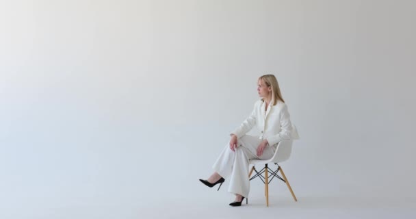 Αυτάρεσκη Γυναίκα Κάθεται Χάρη Μια Καρέκλα Ένα Καθαρό Λευκό Φόντο — Αρχείο Βίντεο