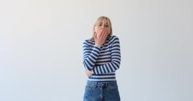 Bir kadın temiz beyaz bir arka planda yorgunluk belirtileri göstermesine rağmen hala neşe saçıyor. Kollarını esnetir ve gerer, yorgunluk gösterir ama aynı zamanda memnuniyet de verir..