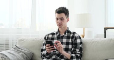 Kafkas kökenli neşeli bir adam oturma odasındaki bir kanepede rahatça oturur ve telefonunu kullanarak içten bir kahkaha atar. Bulaşıcı gülüşü boşluğu sıcaklık ve mutlulukla dolduruyor..