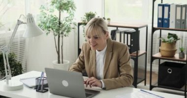İş kadını e-postalarını kontrol ederken ve sevinçle dolu heyecan verici haberler alırken görülüyor. Mesajı dizüstü bilgisayarında okurken yüzü sevinçle parlıyor ve hayretle haykırıyor..
