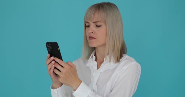 Parlak Gülüşlü Bir Kadın Telefonuyla Mavi Bir Arka Plana Mesaj — Stok video