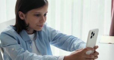 Öğrenci elinde telefon tutarken gerçekten şaşırmış görünüyor. Şaşkın bakışları bir şaşkınlık ya da keşif anını yakalıyor ve etkileşimine bir entrika unsuru ekliyor..