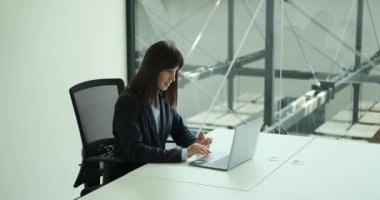 İş başarılarından zevk alan neşeli ve neşeli bir kadın. Yüzü mutlulukla parlıyor, kariyerinde bir dönüm noktasına ulaşmanın heyecanını yansıtıyor..