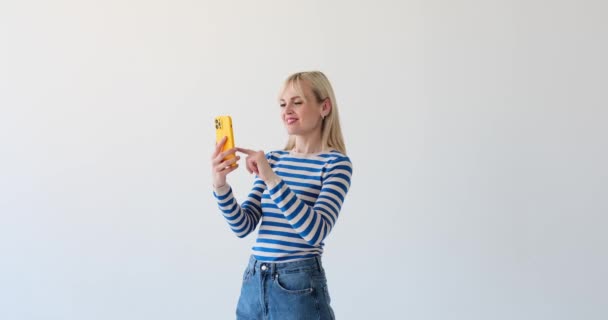 Усміхнена Жінка Спостерігається Білому Тлі Поглинута Переглядом Своєму Телефоні Щасливий — стокове відео