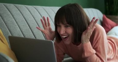 Neşeli bir Kafkas kadını dizüstü bilgisayarın önünde, iyi haberleri kutlarken mutluluğu yayarken görülebilir. Onun coşkulu ifadesi dijital dünyada bir zafer anını ve pozitifliği yansıtıyor..