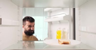 Akşamdan kalmalıkla uğraşan bir adam buzdolabını açar ve soğuk su içerek rahatlama arar. Davranışları, şenlik gecesinden sonra sabah saatlerinde su içmenin yaygın çaresini yansıtıyor..