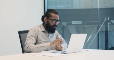 Ofisin canlı atmosferinde Hintli bir ofis çalışanı video görüşmesi sırasında gerçek bir gülümsemeye bürünür. Olumlu haberleri ya da deneyimleri paylaşırken gözleri parlıyor..
