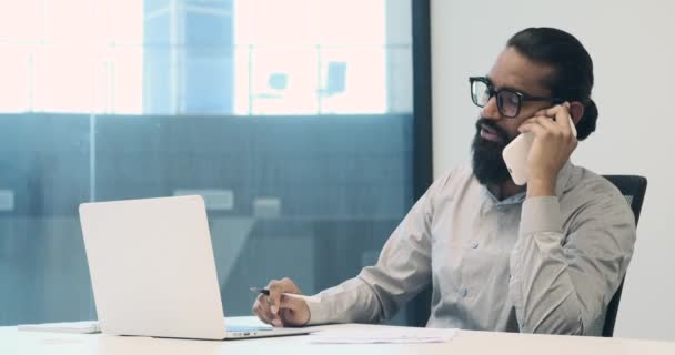 Індійський Бізнесмен Балансує Телефонний Дзвінок Під Час Роботи Своєму Ноутбуці — стокове відео