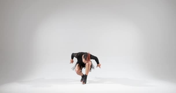 男は自信を持って白い背景にスタジオの設定でスカートを着用しながらダンスのスキルを披露します 彼の芸術的でスタイリッシュな動きは視覚的に魅力的でユニークなパフォーマンスを作成します — ストック動画