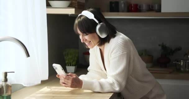 Canlı Beyaz Bir Kadın Kulaklık Takıyor Telefonunun Keyfini Çıkarıyor Mutfağın — Stok video