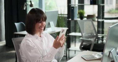 İş kadını işten biraz uzaklaşır ve telefonunu kullanır. Bu dinlenme anında mesajları yakalar, bildirimleri kontrol eder ya da yoğun gününden kısa bir süre uzaklaşmaktan zevk alır..