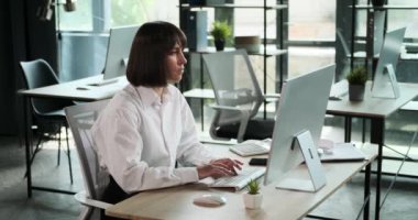 Kendine güvenen bir bayan girişimci modern bir ofiste masa başında oturuyor ve klavyede amacıyla yazıyor. Hedeflerine ulaşmak için çabalarken davranışları güçlü bir kararlılığı yansıtıyor..