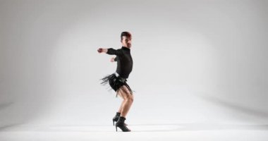 Kafkas kökenli bir dansçı, yüksek topuklu ayakkabılarını temiz beyaz bir arka planda giyerken yeteneklerini sergiliyor. Performansları eşsiz bir zarafet ve stil karışımı yayıyor..