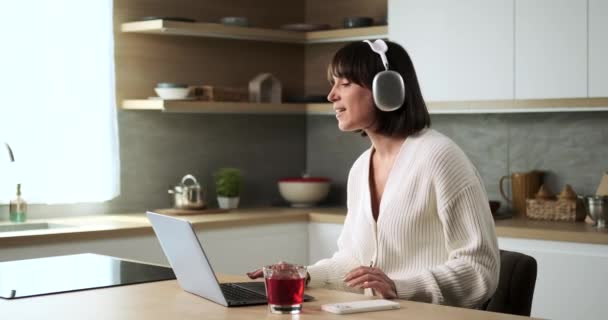 Biała Kobieta Laptopem Słuchawkami Tańczy Rytm Muzyki Kuchni Jej Energiczne — Wideo stockowe