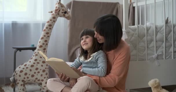 在欢乐的儿童房里 一位快乐的母亲和她的女儿一起看书 他们共同的阅读热情使房间充满了温暖和对讲故事的热爱 — 图库视频影像