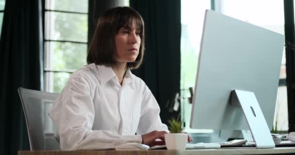 確固たる女性マネージャーは オフィス環境でコンピュータで働いている間 彼女の仕事に完全に魅了されます 彼女の絶え間ない集中は彼女の強い献身を反映しています — ストック動画
