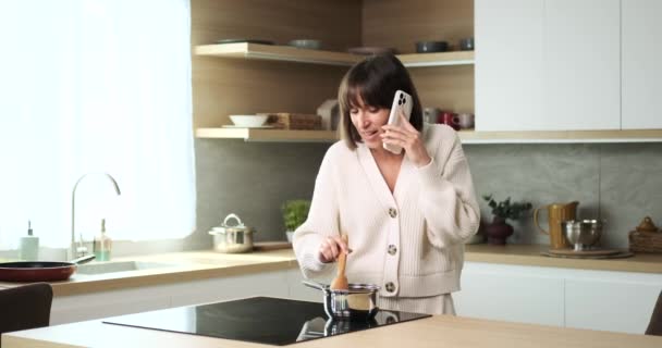 Una Mujer Caucásica Alegre Encuentra Deleite Cocinar Charlar Por Teléfono — Vídeos de Stock
