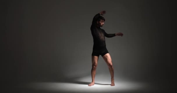 決定的な男は 対照的なライトの遊びの中で激しい集中で彼のダンスのスキルを展示します 彼の意図的で意図的な動きは視覚的に魅了されるパフォーマンスを作り出します — ストック動画