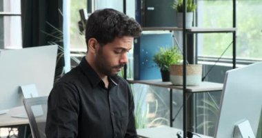 Uykulu Orta Doğulu işadamı, ofiste bilgisayarla çalışıyor. Yorgunluğa rağmen üretken kalmaktaki kararlılığı profesyonel sorumlulukların bir örneği..