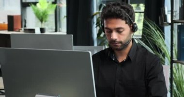 Orta Doğulu bir ofis çalışanı, bilgisayarla verimli bir iş görüşmesi yapıyor. Odaklanmış bir tavırla iş iletişiminin karmaşıklıklarına yön verip profesyonelliği sağlıyorlar..