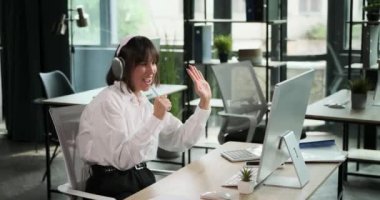 Ofiste çalışırken kulaklık takan bir ofis çalışanı sevinçle şarkı söyler. Neşeli şarkıları çalışma alanına bir neşe katıyor, neşe anlarını bulma yeteneğini yansıtıyor..