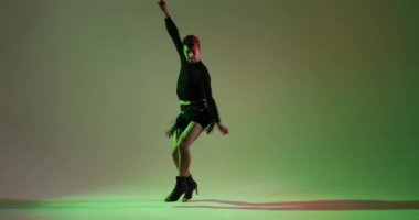 Kafkas kökenli hevesli bir dansçı canlı yeşil bir arka planda performans sergilerken enerji patlaması yaşıyor. Dinamik ve canlı dans hareketleri heyecan verici bir görsel deneyim yaratıyor..