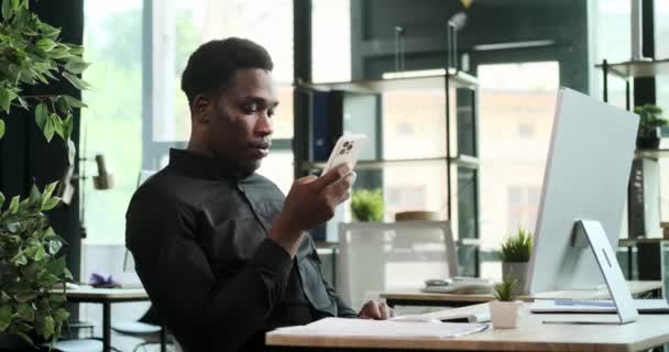 黒人の起業家が職場で電話をかけた このシーンは ビジネス上の問題を管理する彼の効率的なコミュニケーションとマルチタスクのスキルを反映しています — ストック動画