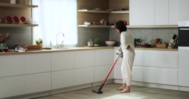 不満な女性は台所で掃除機を使用しています 彼女の不満は 彼女が掃除タスクを実行し キッチンであまり快適な雰囲気を作成するように明らかです — ストック動画