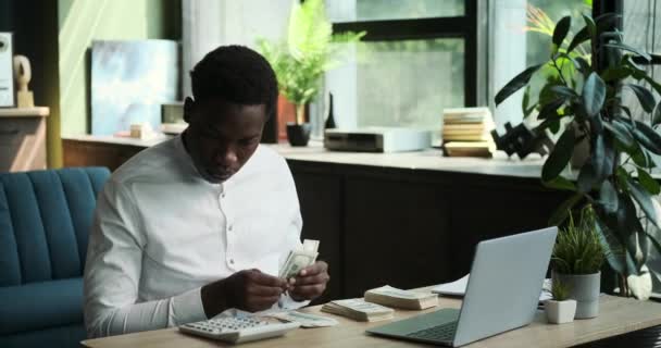 一个勤勤恳恳的黑人商人坐在办公桌前 在计算器的帮助下仔细地计算着现金 在财务管理的这一背景下 他对财务问题的专注态度是显而易见的 — 图库视频影像