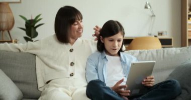 Anne ve oğlu oturma odasındaki kanepede otururken dijital tablet kullanarak sohbet ediyorlar. Diyalogları ve bağlantıları iletişimsel bir atmosfer yaratır..