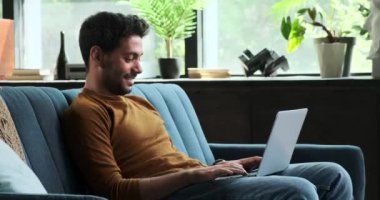 Neşeli Orta Doğulu bir adam laptopunu kullanırken bir video görüşmesi yapıyor. Sıcak gülümsemesi ve aktif katılımı, uzaktan iletişimin olumlu ve etkili doğasını vurguluyor..