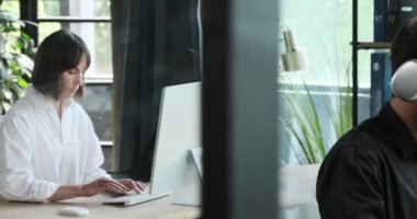 Çalışan ofiste video görüşmesi için bir bilgisayardan faydalanıyor. Etkili iletişim odakları, teknolojinin işbirliği ve takım çalışmasının kolaylaştırılmasındaki rolünü vurguluyor.